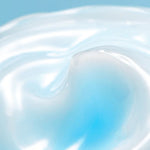 Close-up of smooth, glossy blue-tinted Torriden Dive In Soothing Cream against a light blue background, showcasing its swirling texture.