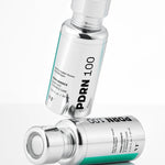 Two silver bottles of VT Cosmetics PDRN Essence 100, designed for elasticity and wrinkle care, displayed on a reflective surface.